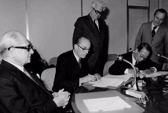 Die schwarz-weiss Fotografie zeigt René Maheu, den damaligen Generaldirektor der UNESCO bei der Unterzeichnung der Welterbekonvention 1972. 